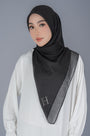 A woman wearing a black hijab with a wide gray border and small silver rhinestone accents, paired with a white long-sleeve top, against a solid gray studio background.